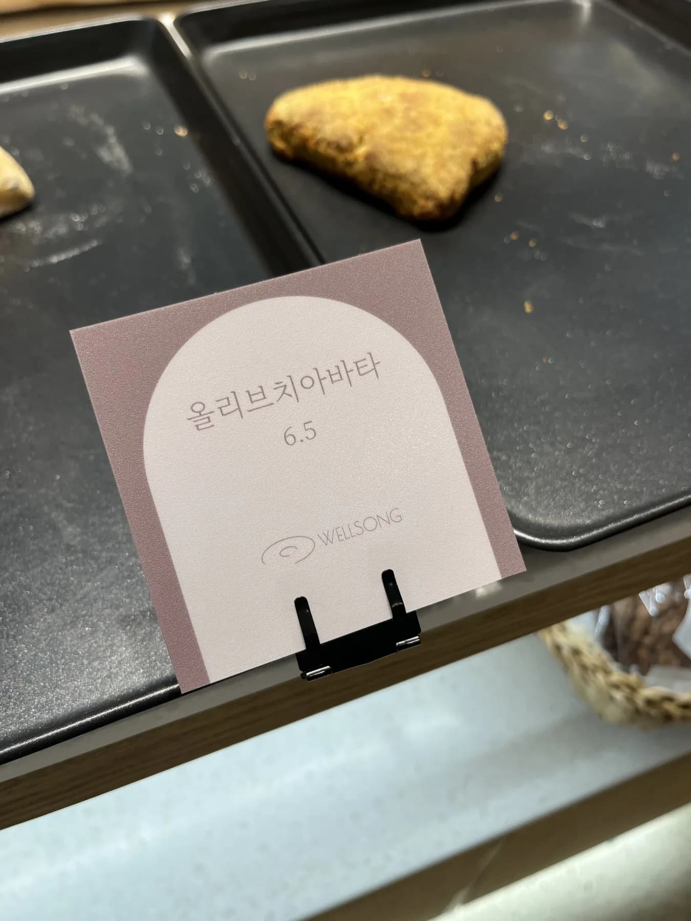 카페 웰송 베이커리 진열대의 제품 안내 사인